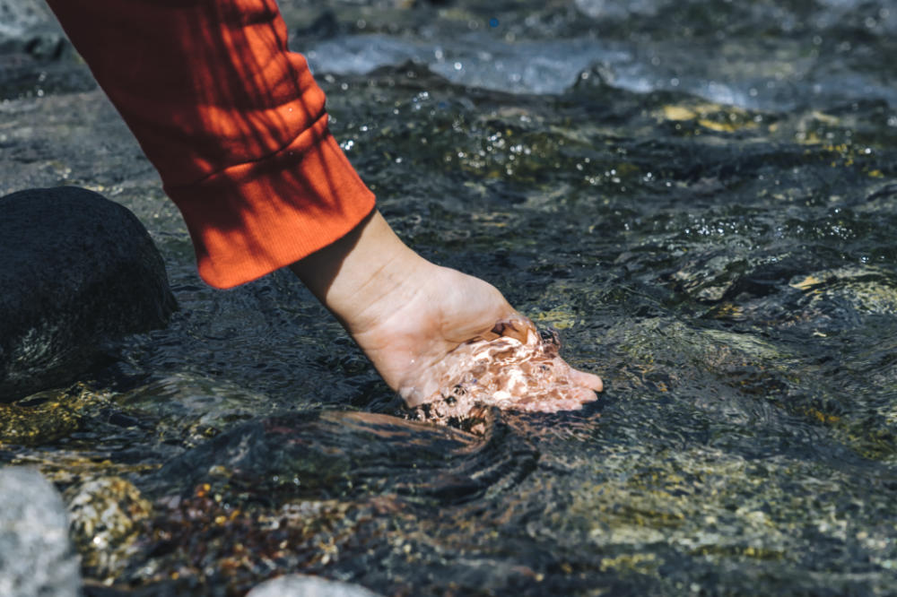 Mano que recoge agua de río